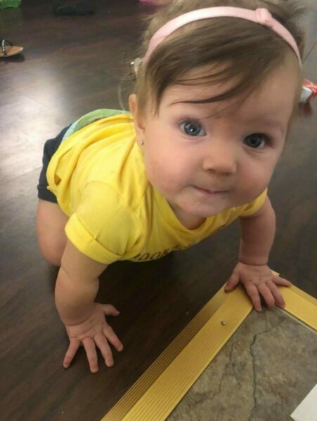 Brielle, a girl with a cochlear implant, pictured here as a baby crawling and staring up at the camera. 