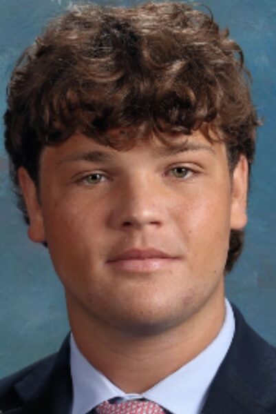 Danny, who has become very involved in both school and hockey after his cochlear implants, posing for a photo of his headshot. He is wearing a suit and tie. 