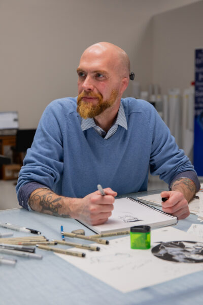 Will, born with microtia and atresia and a Baha 6 Max upgrade recipient, drawing at his desk.