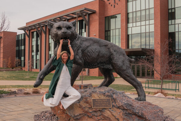 Rachel smiling and posing with her college mascot at her college graduation; Baha sound processor features.