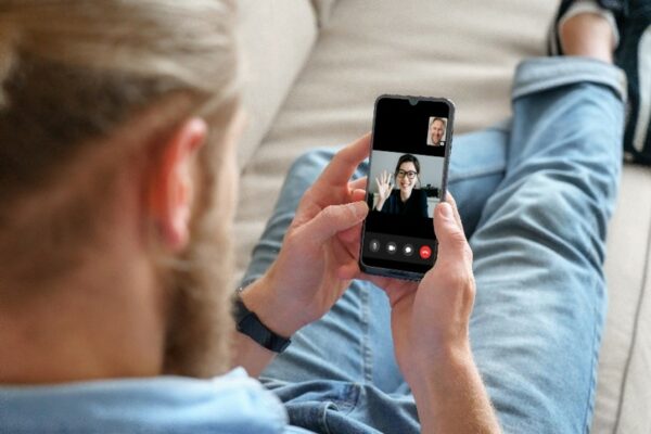 Cochlear's Connected Care solution, Remote Assist, demonstrates a person sitting on their couch at home taking a video call with his audiologist in real time.