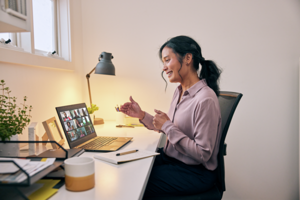 Woman sits at her desk returning to work after a cochlear implant, while on a video conference on her computer. A Cochlear Nucleus 8 Sound Processor is visible above her left ear.