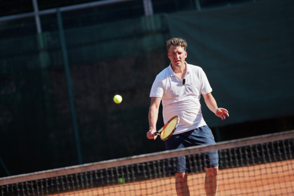 A man in athletic attire being active with his cochlear implant while playing tennis