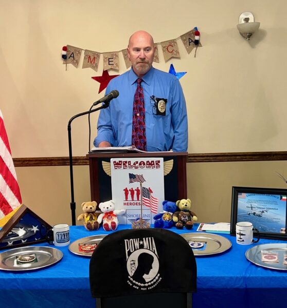 Erik, who experienced sudden sensorineural hearing loss from Covid, standing at a podium speaking with police and military information in front of him.