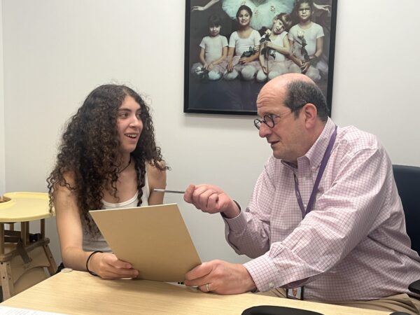 Brynn, a Cochlear™ recipient talking with her audiologist, Dr. Shapiro, he is referencing something on a sheet of paper.
