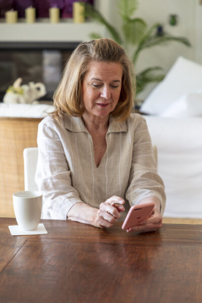 A woman sitting at table with coffee is using her smartphone