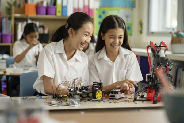 A student with a Kanso sound processor and her partner, smiling in class working on a science experiment.