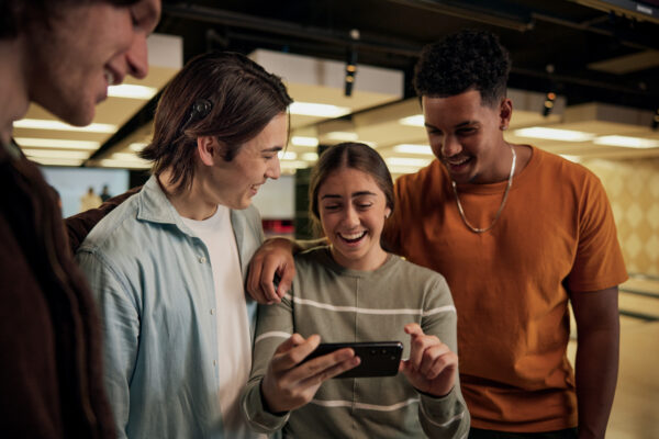 A Cochlear Nucleus recipient with a group of friends smiling and talking at a bowling alley.