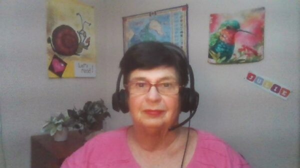 Julie, a bimodal cochlear implant recipient, smiling with a headset on teaching a remote ESL class; cochlear implant bimodal hearing solutions and music.