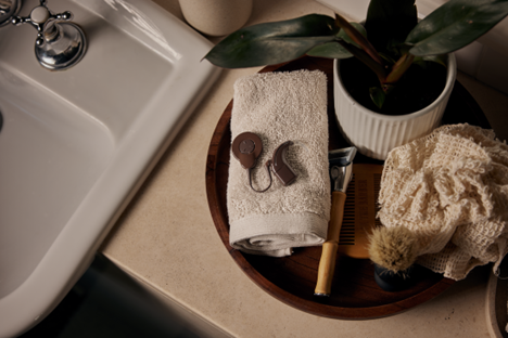 A Cochlear Nucleus 8 Sound Processor sits on a folded hand towel next to a bathroom sink.