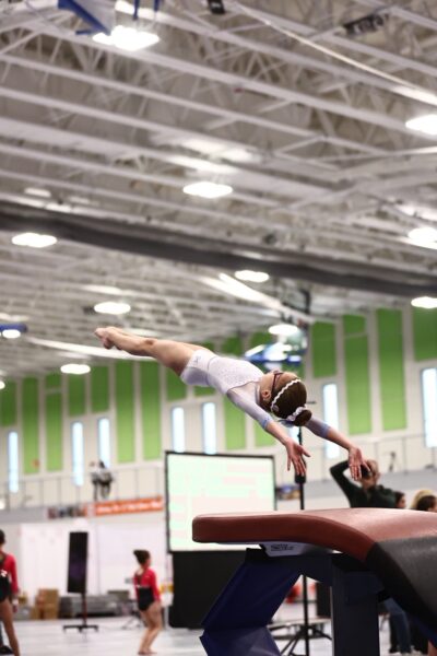 Savannah, whose hearing care team helped guide her to a cochlear implant. Pictured flipping through the air in a vault routine. 