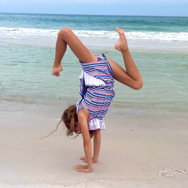 Savannah, whose hearing care team helped guide her to a cochlear implant. Pictured doing a handstand on the beach in front of the ocean. 