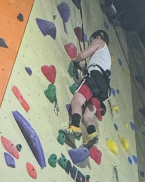 Anthony, a young boy with single-sided deafness and a cochlear implant, shown rock climbing at an indoor facility.