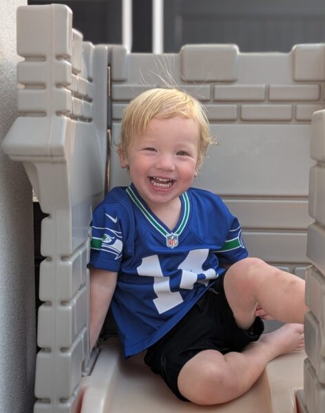 Lawson, a toddler who received a cochlear implant, giggling while sitting in a beige toy castle.