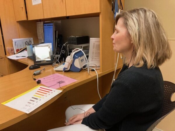 A picture of Shanna, who received a cochlear implant due to progressive hearing loss, sitting at an audiology appointment where her device is being programmed. 