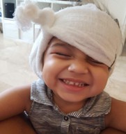 Amelia, who received early intervention after a bilateral sensorineural hearing loss diagnosis, smiling with a head wrap on.